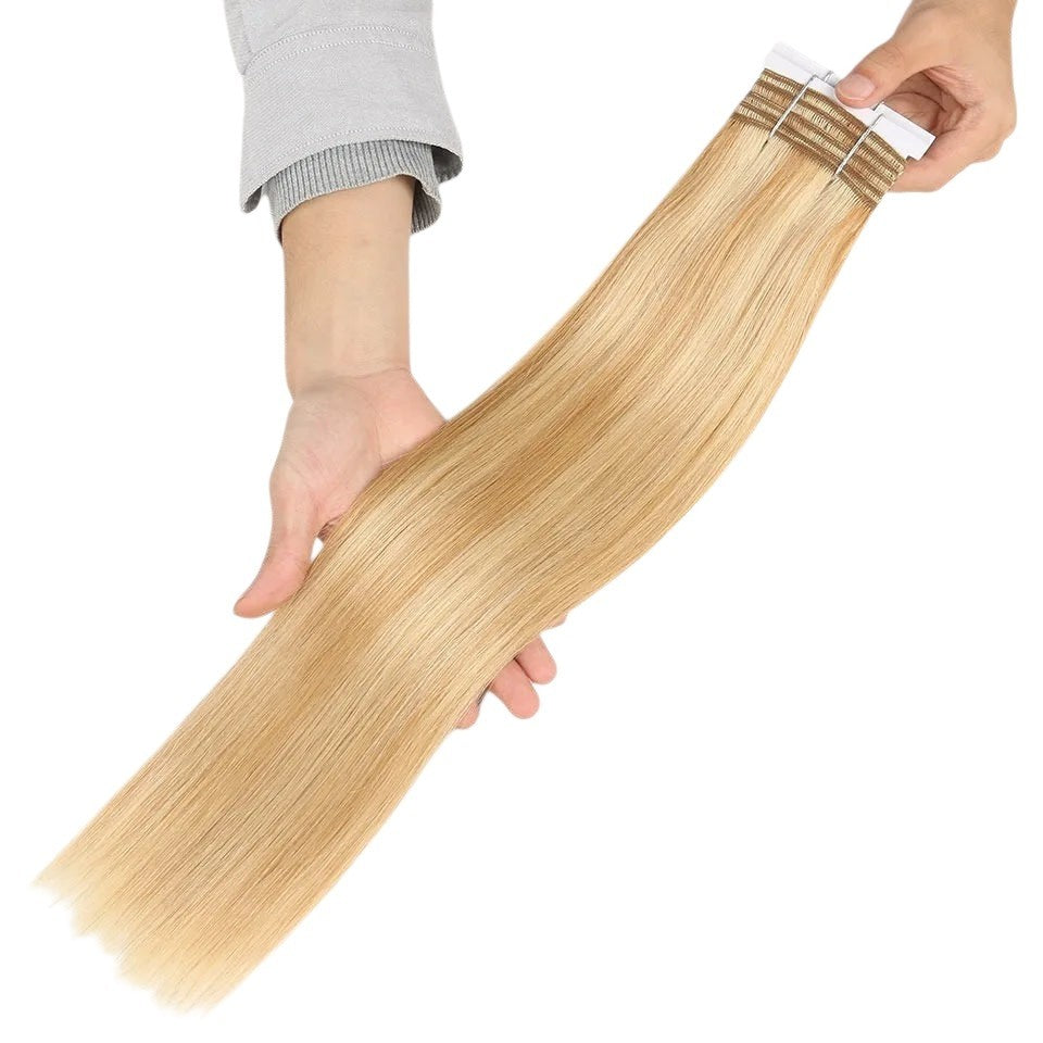 RitzWigs blonde P27/613 human hair tape-in extensions with a silky straight texture held in hands