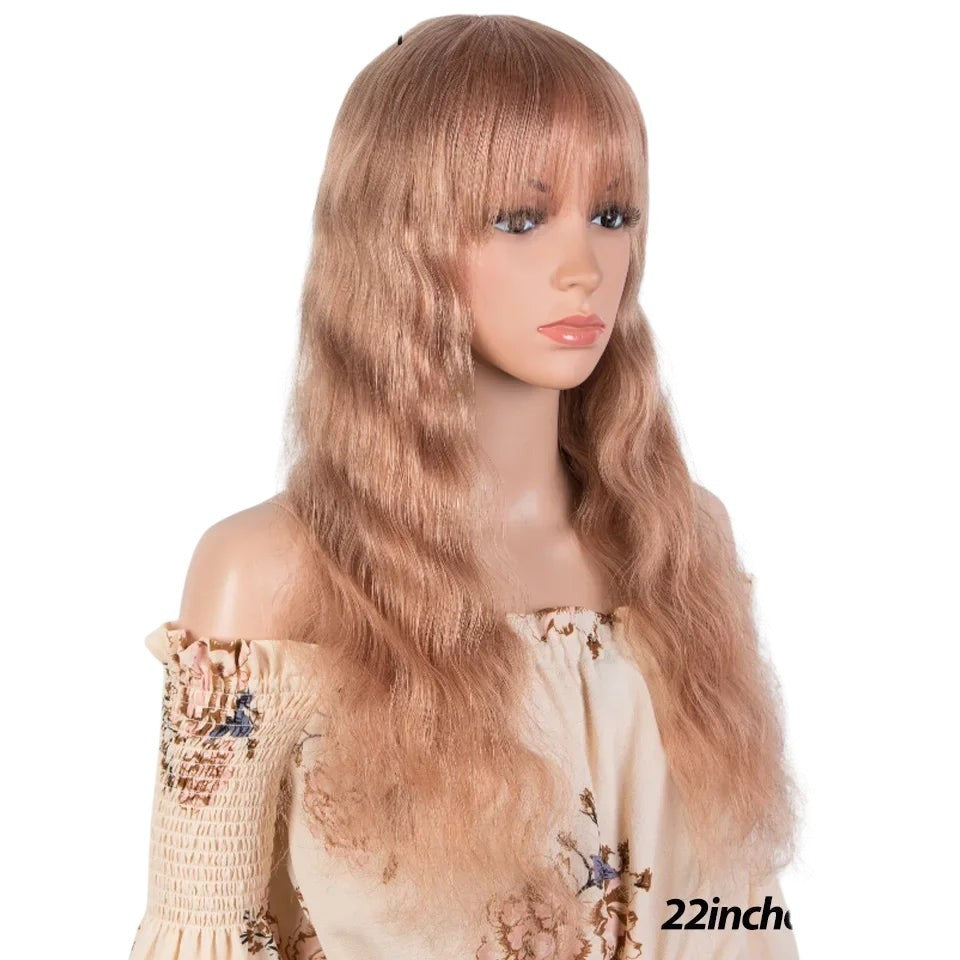 RitzWigs blonde wavy human hair wig with bangs on a mannequin, 22 inches long, featuring a natural body wave texture.