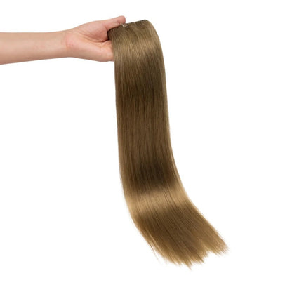 RitzWigs straight human hair extension weft in a light brown shade held in a hand against a white background